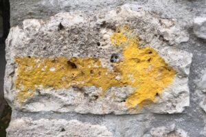 ietwat vage gele pijl op brokkelige muur