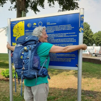 vrouw met rugzak omarmt bord met Jacobspaden Hasselt