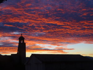 silhouet van een kerk tegen rood oplichtende avondhemel