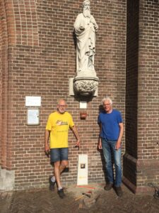 Pierre en de koster van de Sint Jacobskerk met een caminopaal tegen de muur