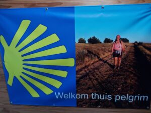 Spandoek met afbeelding caminowegwijzer en pelgrim en de tekst Welkom thuis pelgrim