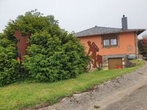 plantsoen voor herberg met een metalen silhouet van een wandelaar en een fietser