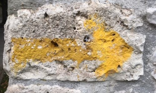 ietwat vage gele pijl op brokkelige muur